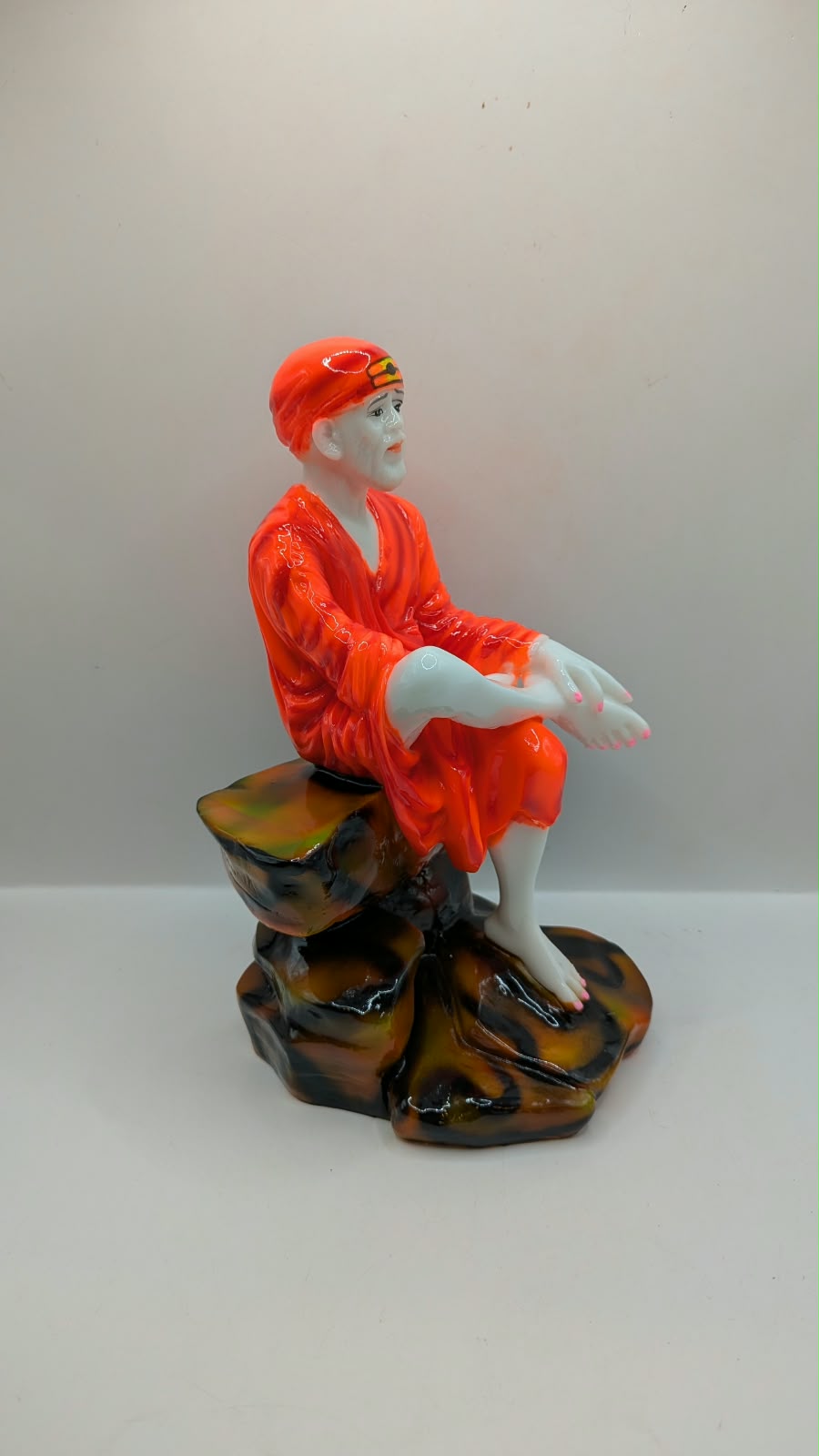 Sai Baba statue on rock seat, side view