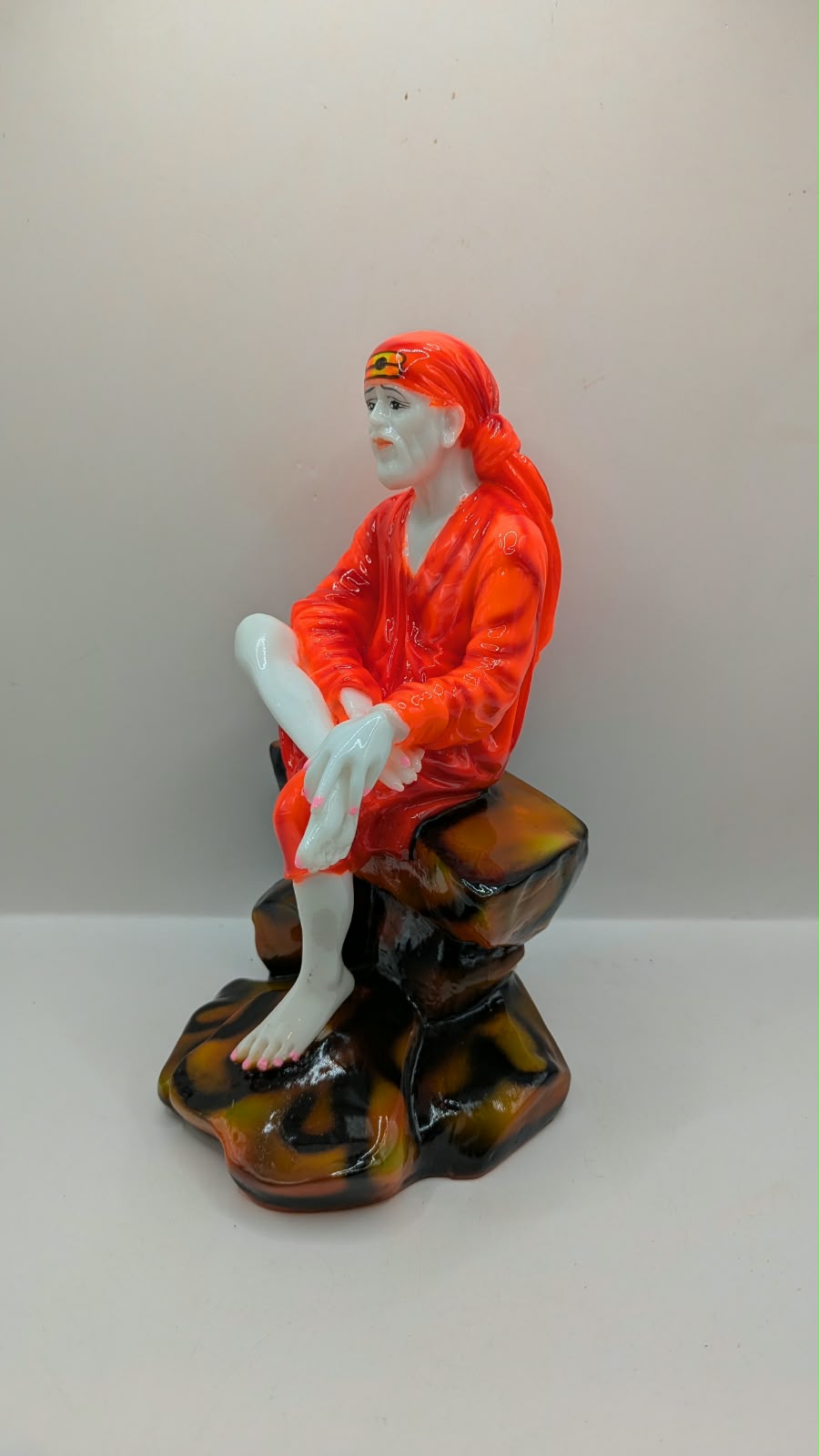 Sai Baba statue on rock seat, other side view