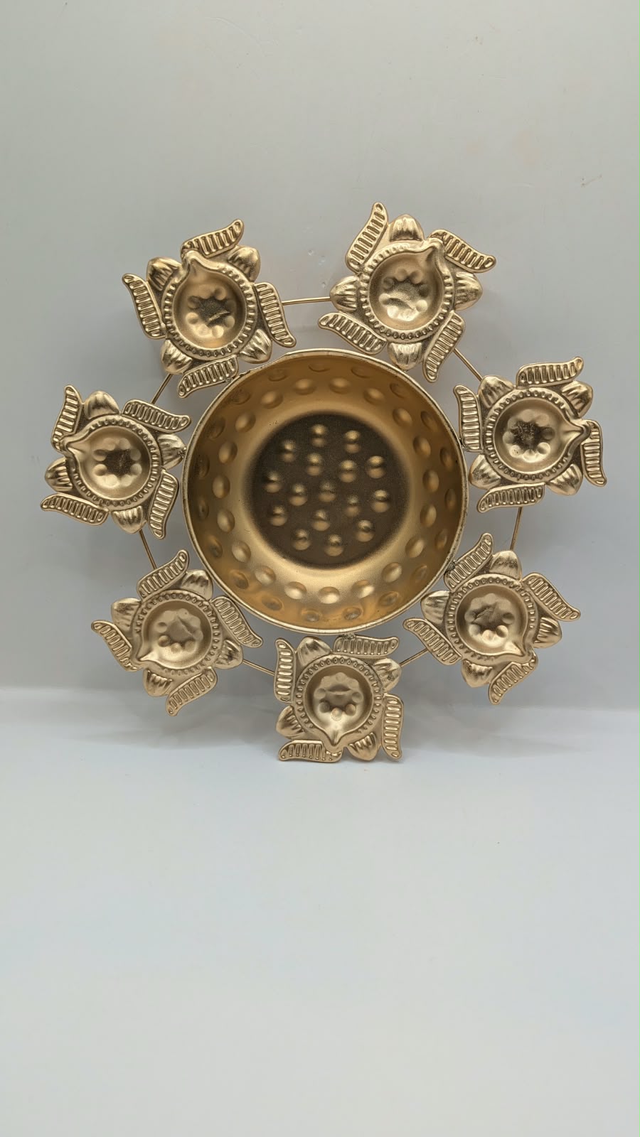 Gold metal urli bowl with 7 lotus diyas, front view