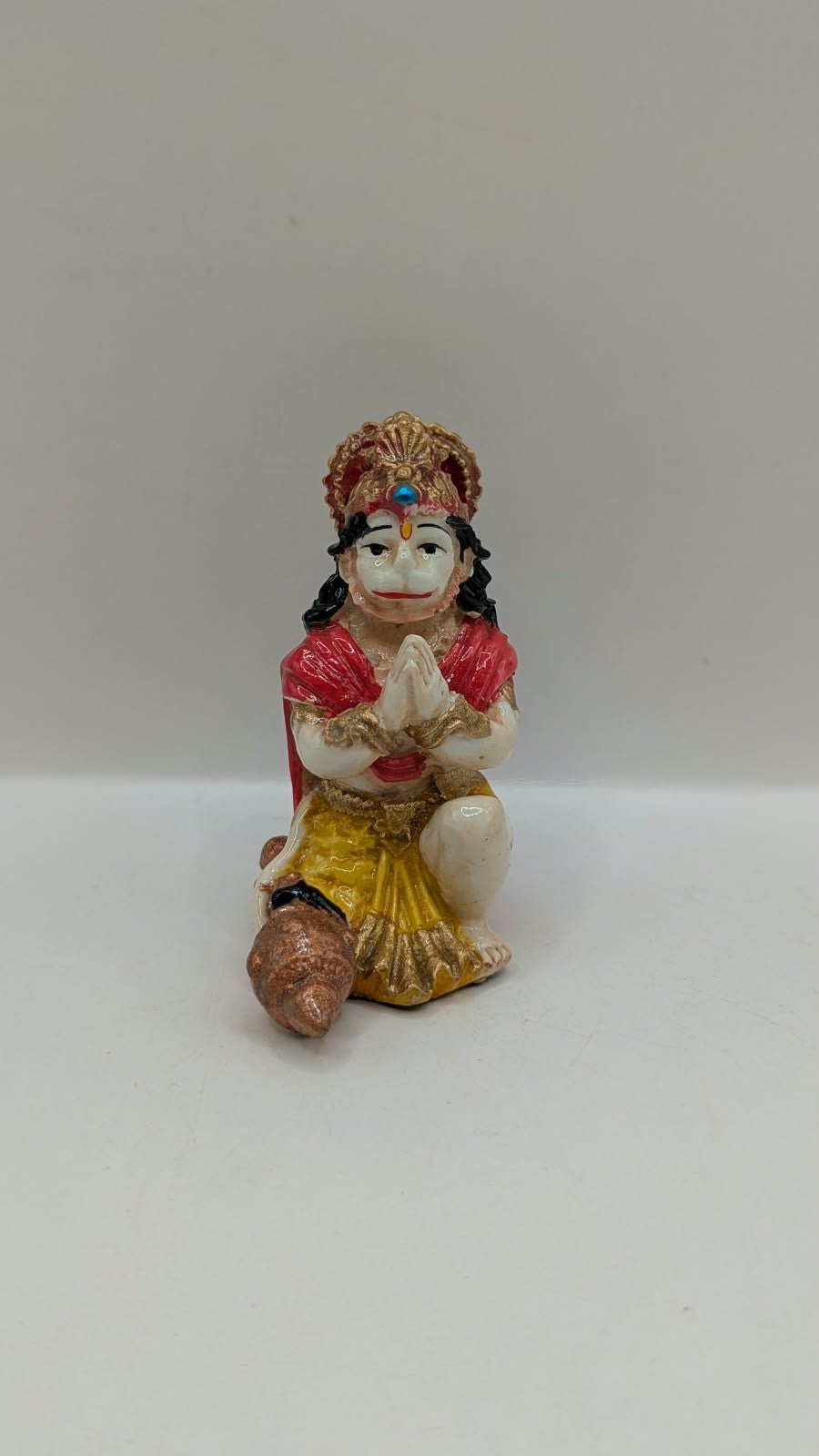Red and yellow praying Hanuman resin statue, front view