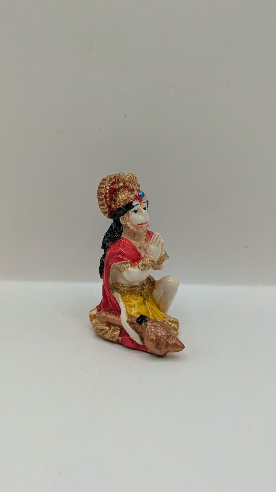 Red and yellow praying Hanuman resin statue, side view