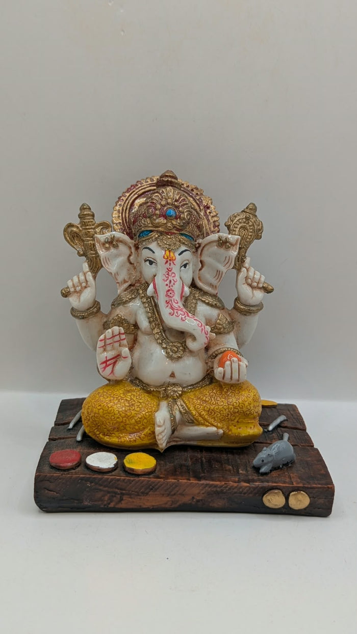 White and yellow Ganesh resin statue on wood-look base, front view