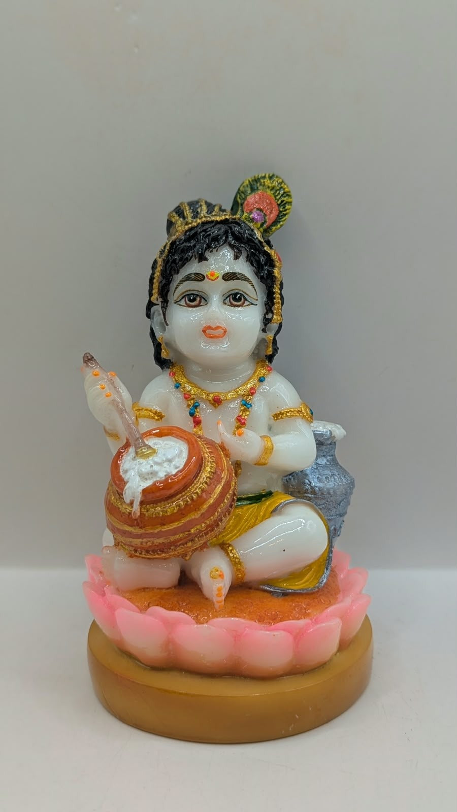 White baby Krishna statue on pink lotus, front view