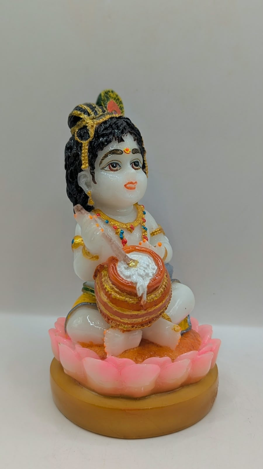 White baby Krishna statue on pink lotus, side view