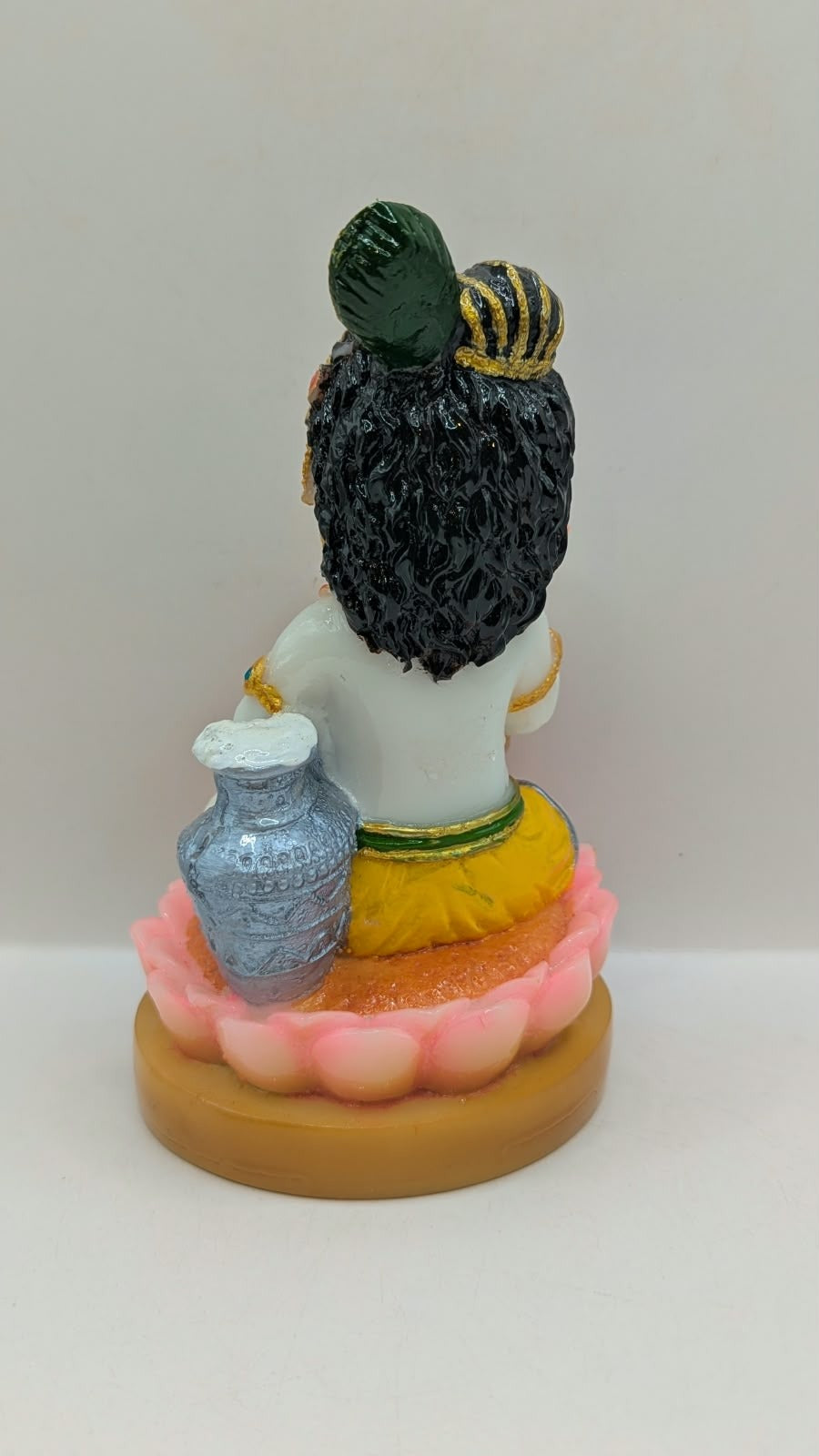White baby Krishna statue on pink lotus, back view