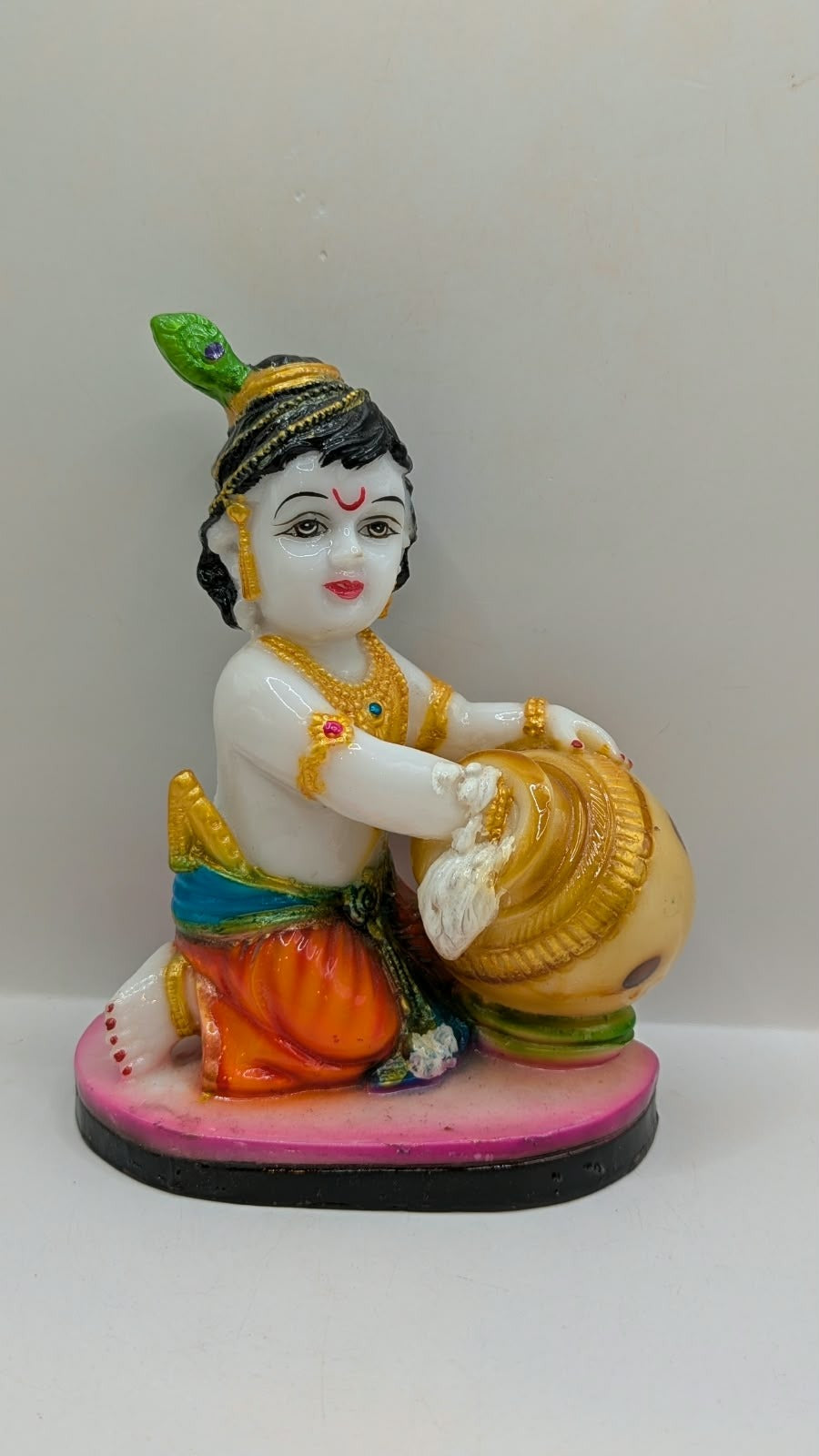 White baby Krishna statue kneeling with butter pot, front view