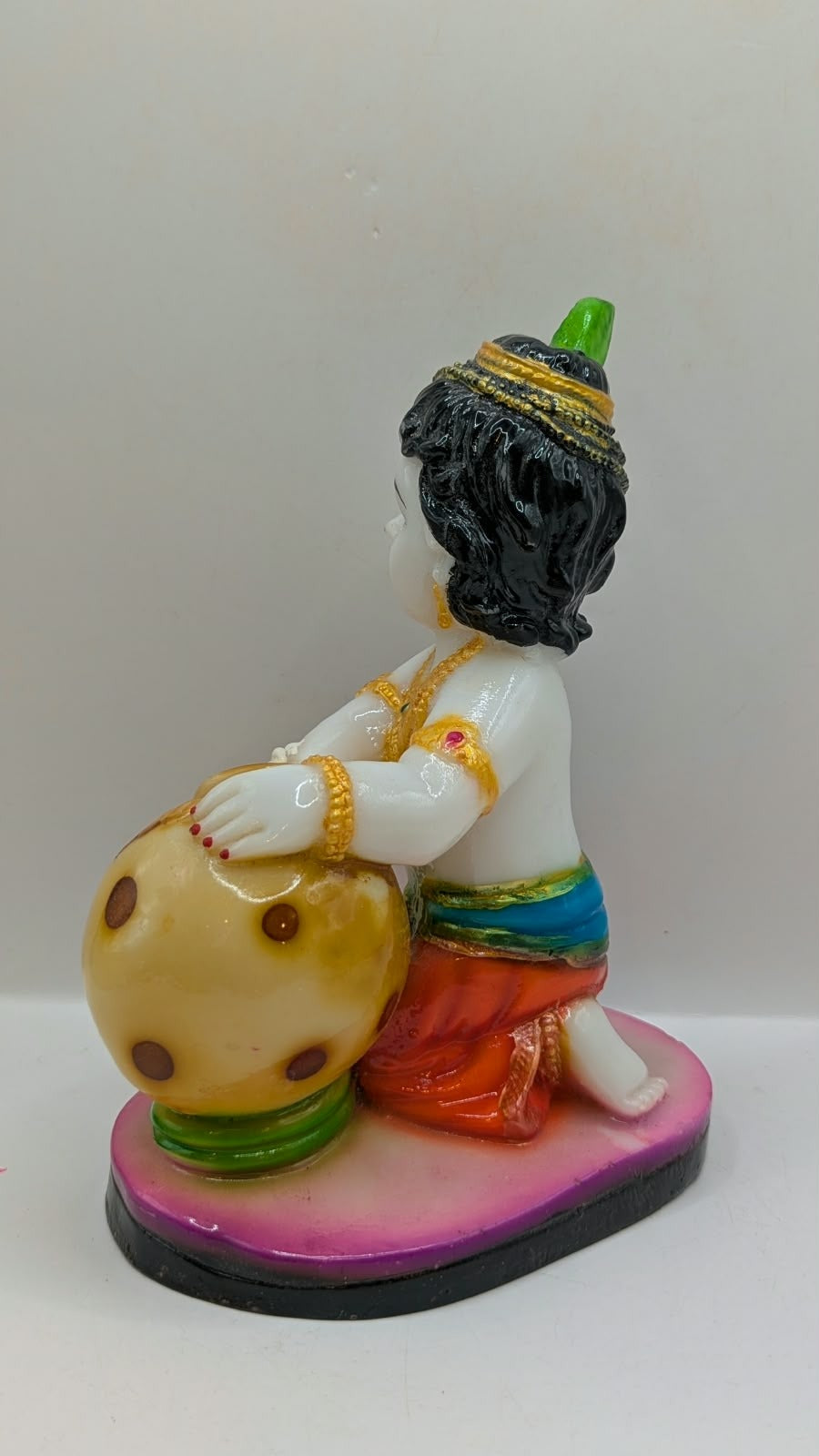 White baby Krishna statue kneeling with butter pot, back view