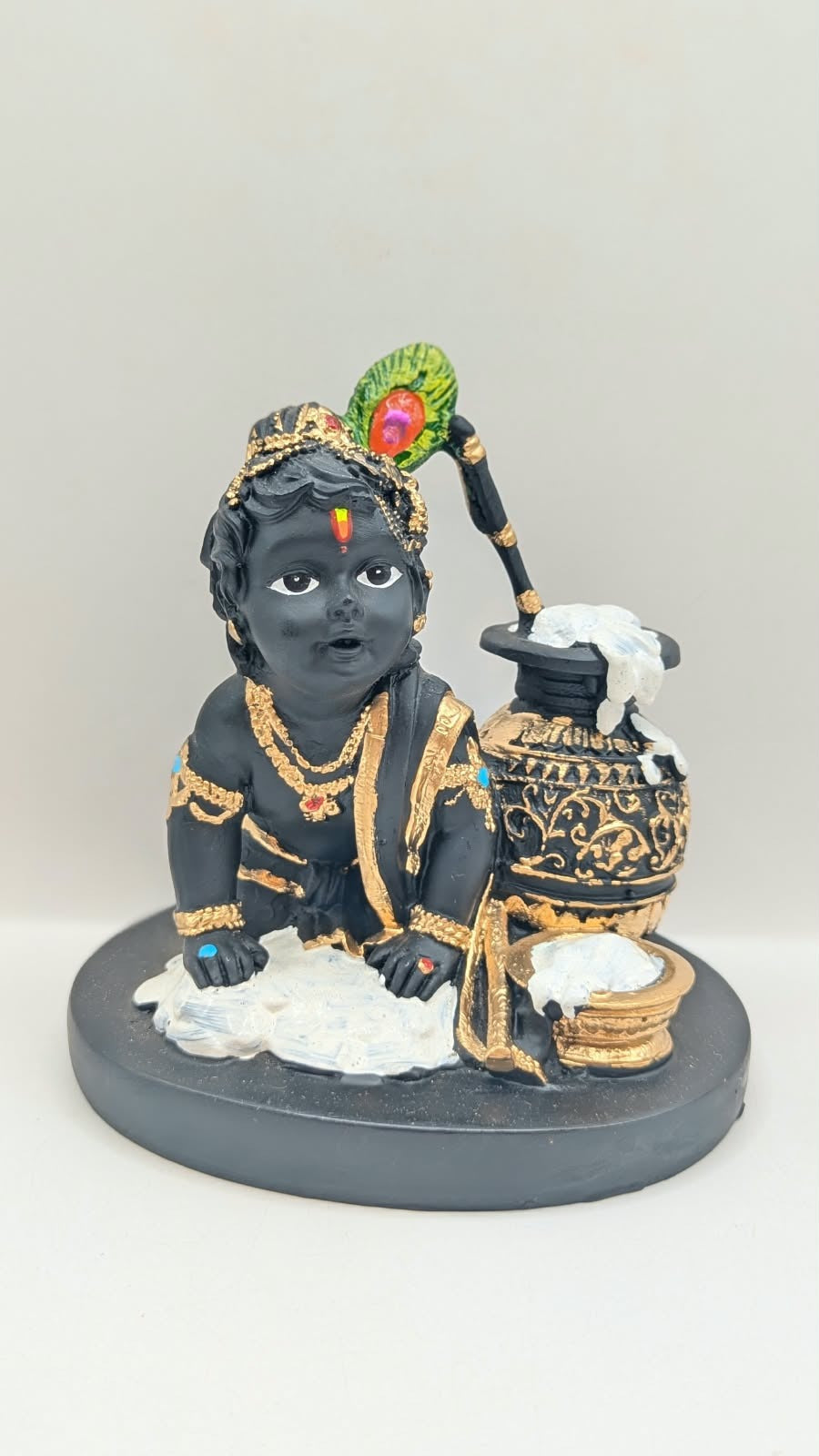 Black and gold baby Krishna statue with butter pot, front view