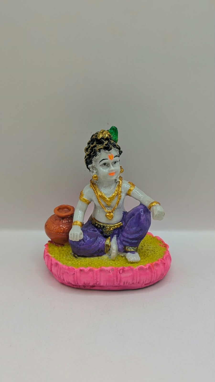 Baby Krishna statue in purple dhoti, side view