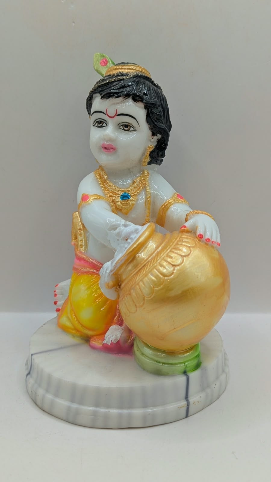Baby Krishna statue hugging gold pot, front view