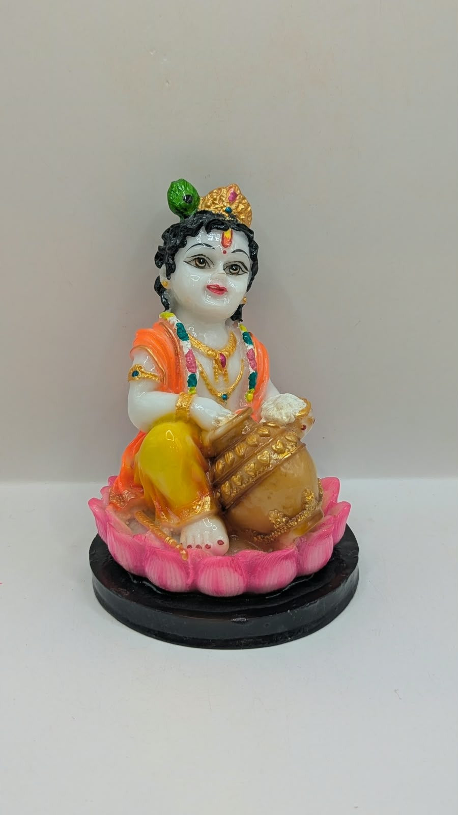 Baby Krishna statue on pink lotus, black base, front view