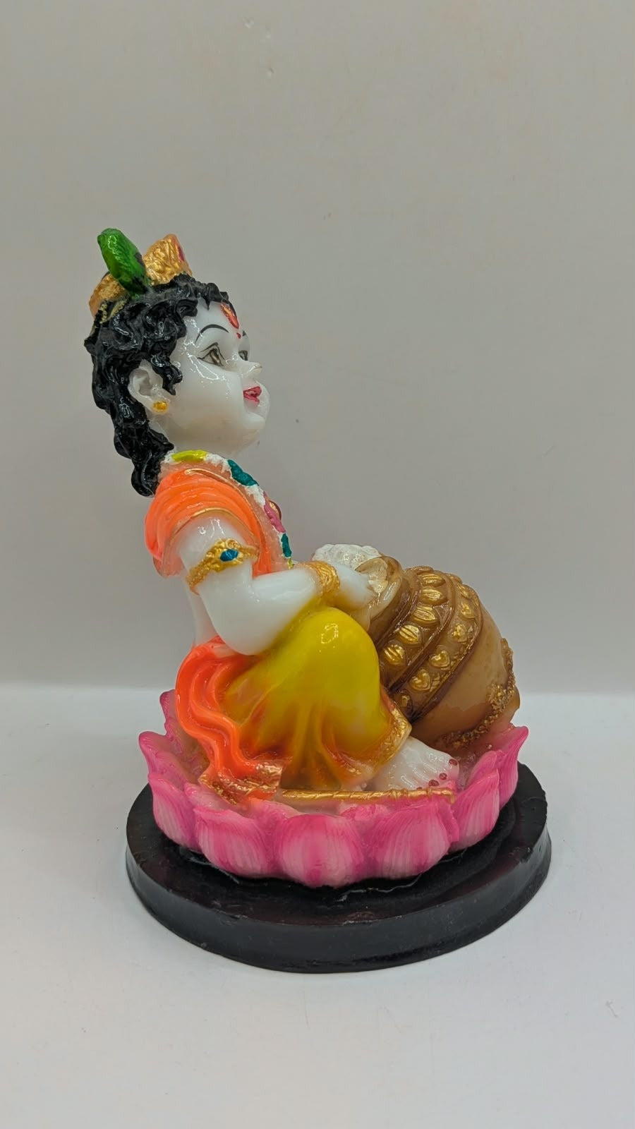 Baby Krishna statue on pink lotus, black base, side view