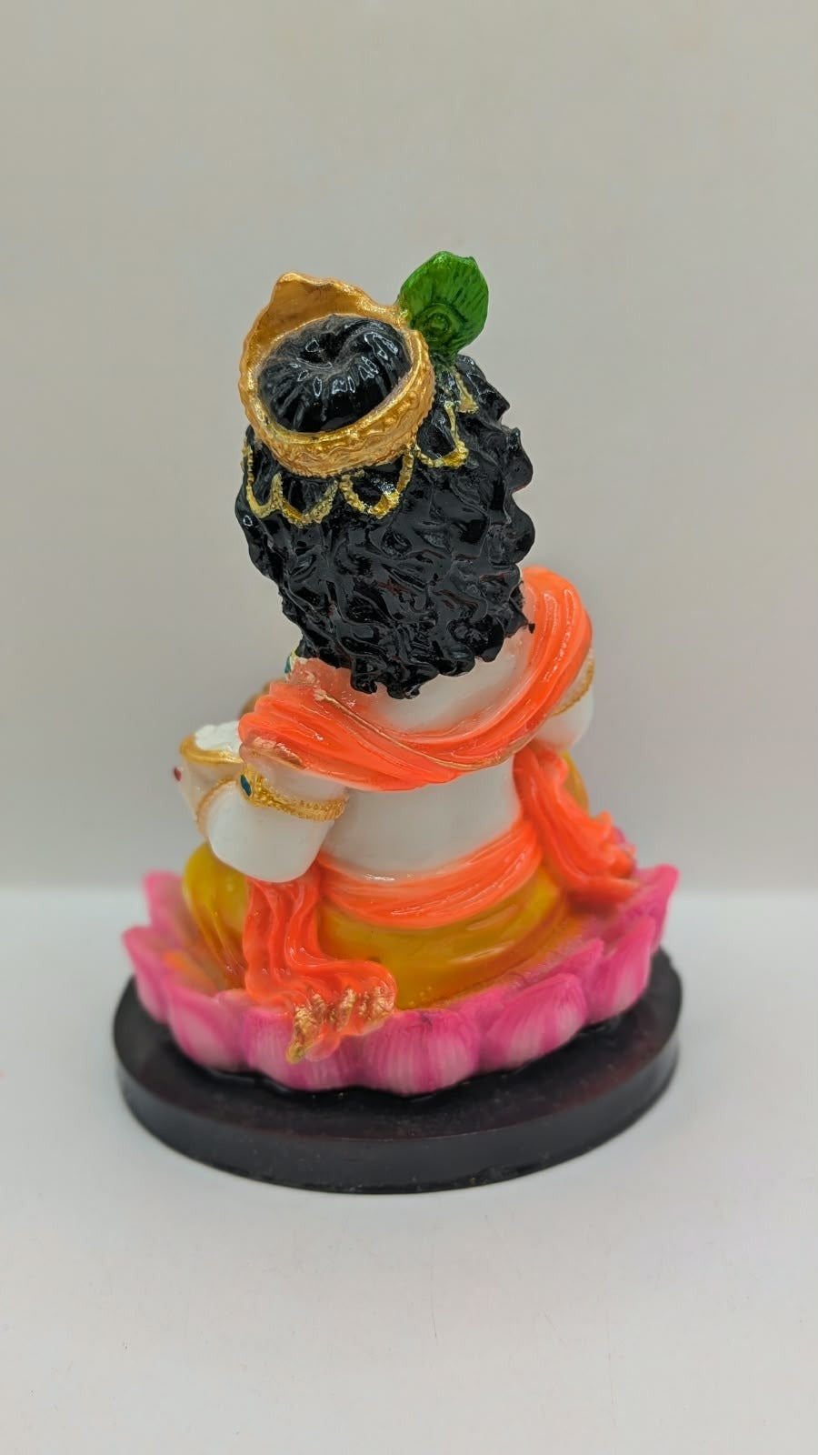 Baby Krishna statue on pink lotus, black base, back view
