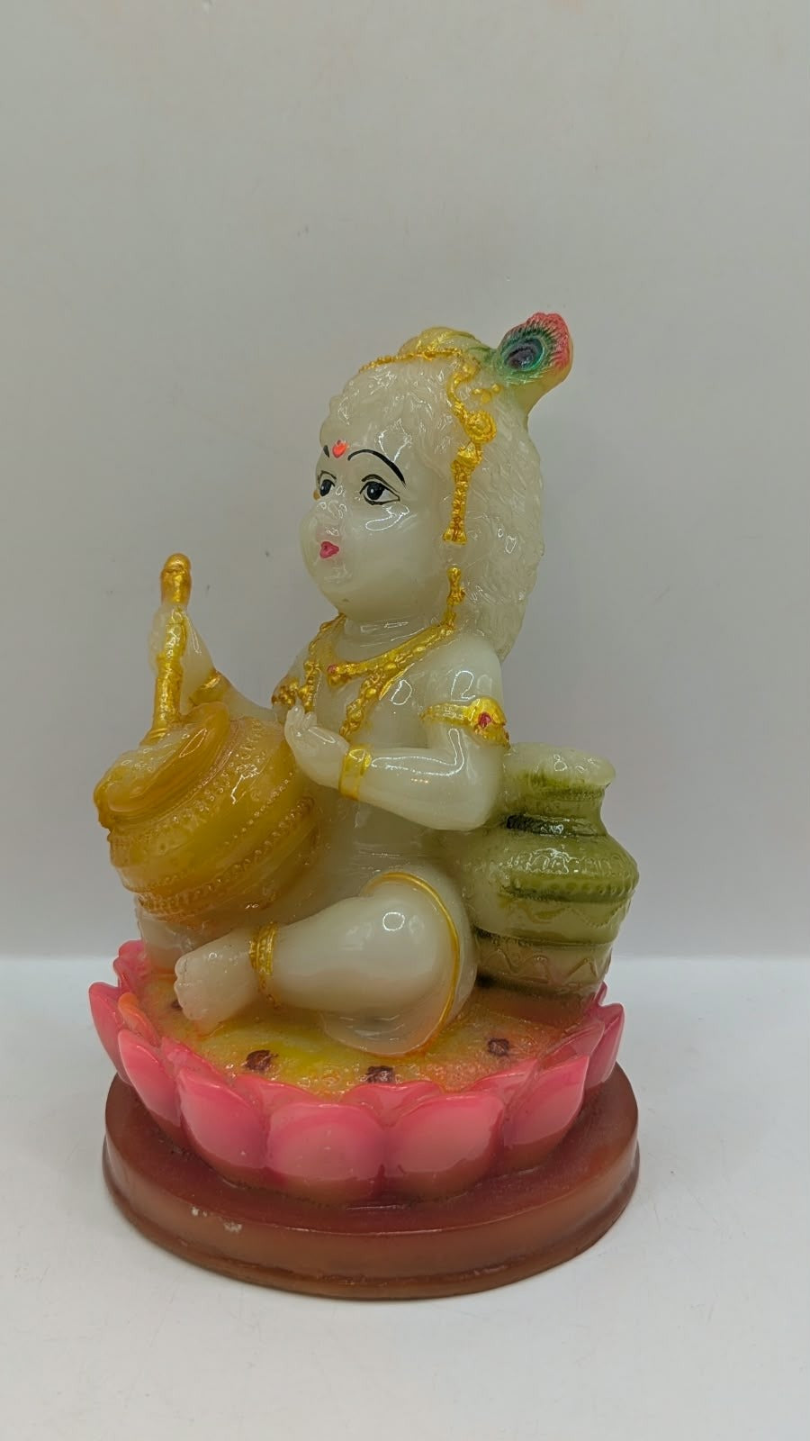 Cream and gold baby Krishna statue on lotus, side view