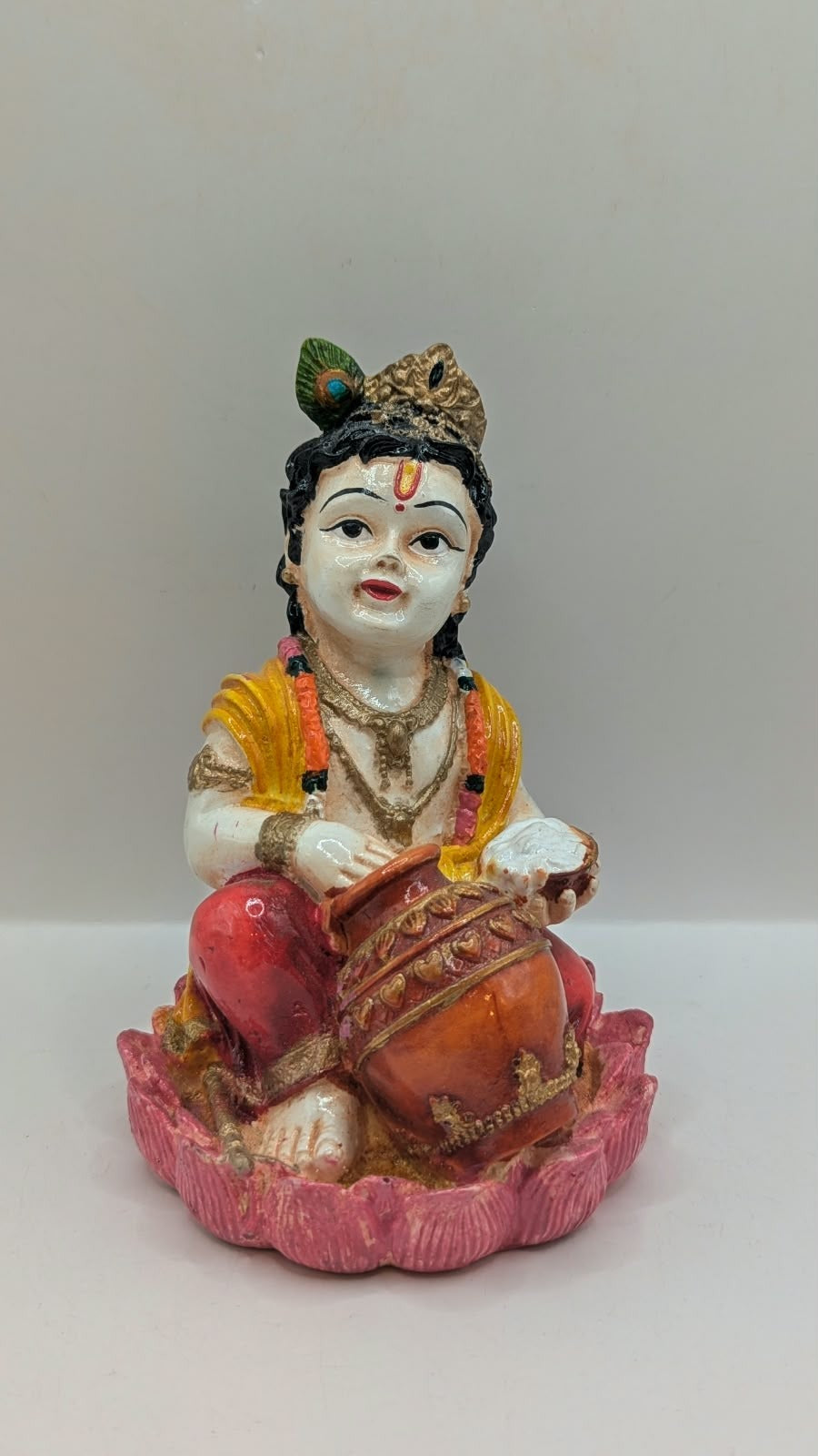 Baby Krishna statue in red dhoti on pink lotus, front view