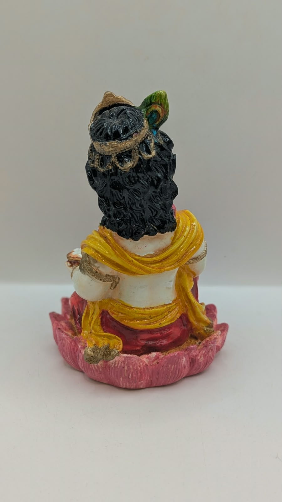 Baby Krishna statue in red dhoti on pink lotus, back view